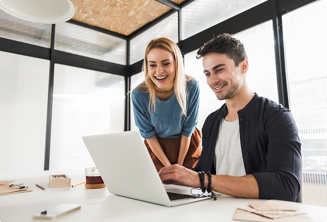 Two happy employees are looking at a laptop
